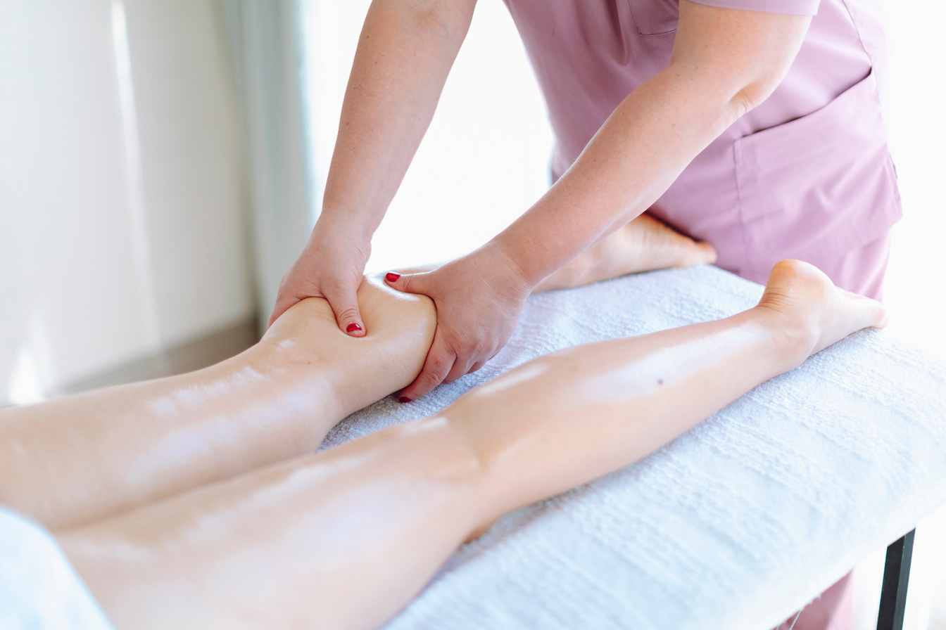 Massage therapist at beauty salon making anti-cellulite massage. Body, leg and foot massage and lymphatic drainage